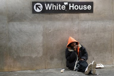 Homeless man in front of sign for the White House