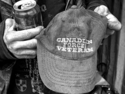 Homeless man holding Canadian Forces Veteran hat