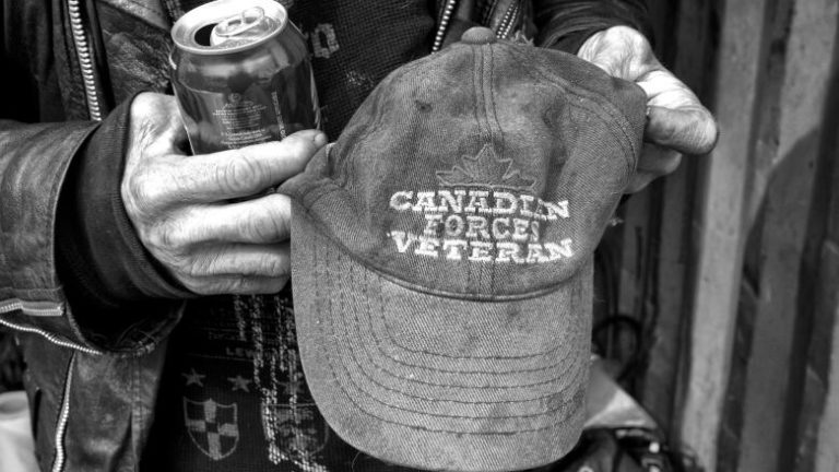 Homeless man holding Canadian Forces Veteran hat