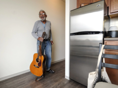 Man holding guitar in new housing