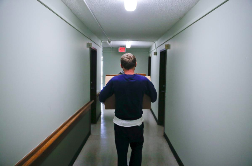 Man walking through hallway holding boxes