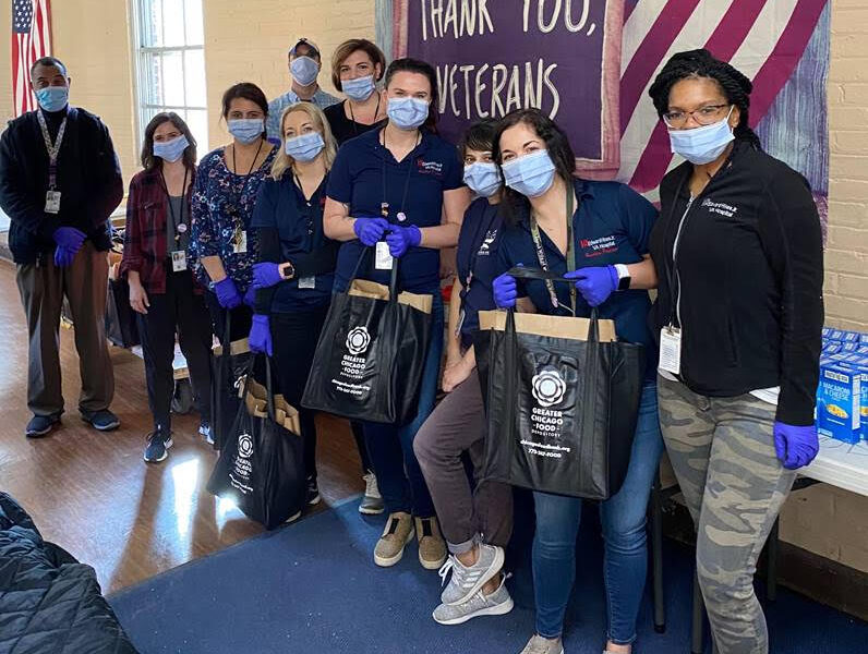 Group with face masks on stands in front of sign saying "Thank you veterans"