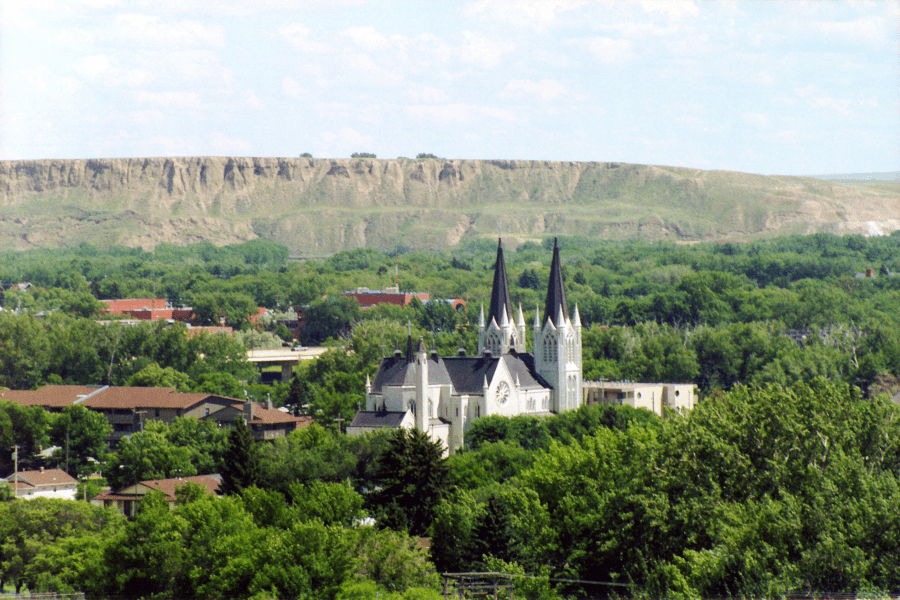 Medicine Valley Landscape, a two-towered church stands above a canopy of green trees.