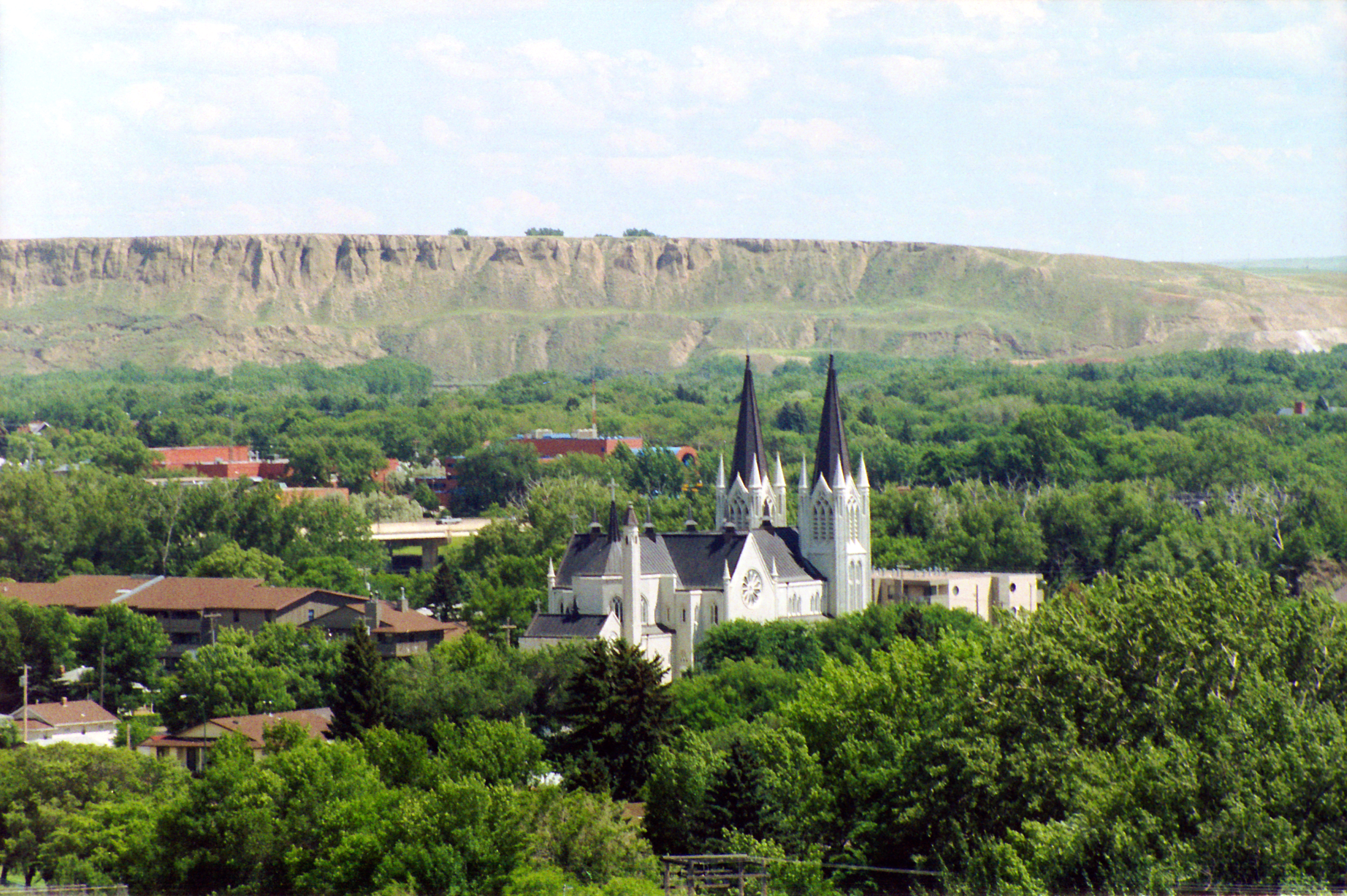 Medicine Valley Landscape, a two-towered church stands above a canopy of green trees.