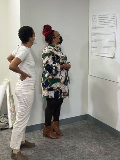Two Black women stand in front of a mapping chart, engaged in the activity.