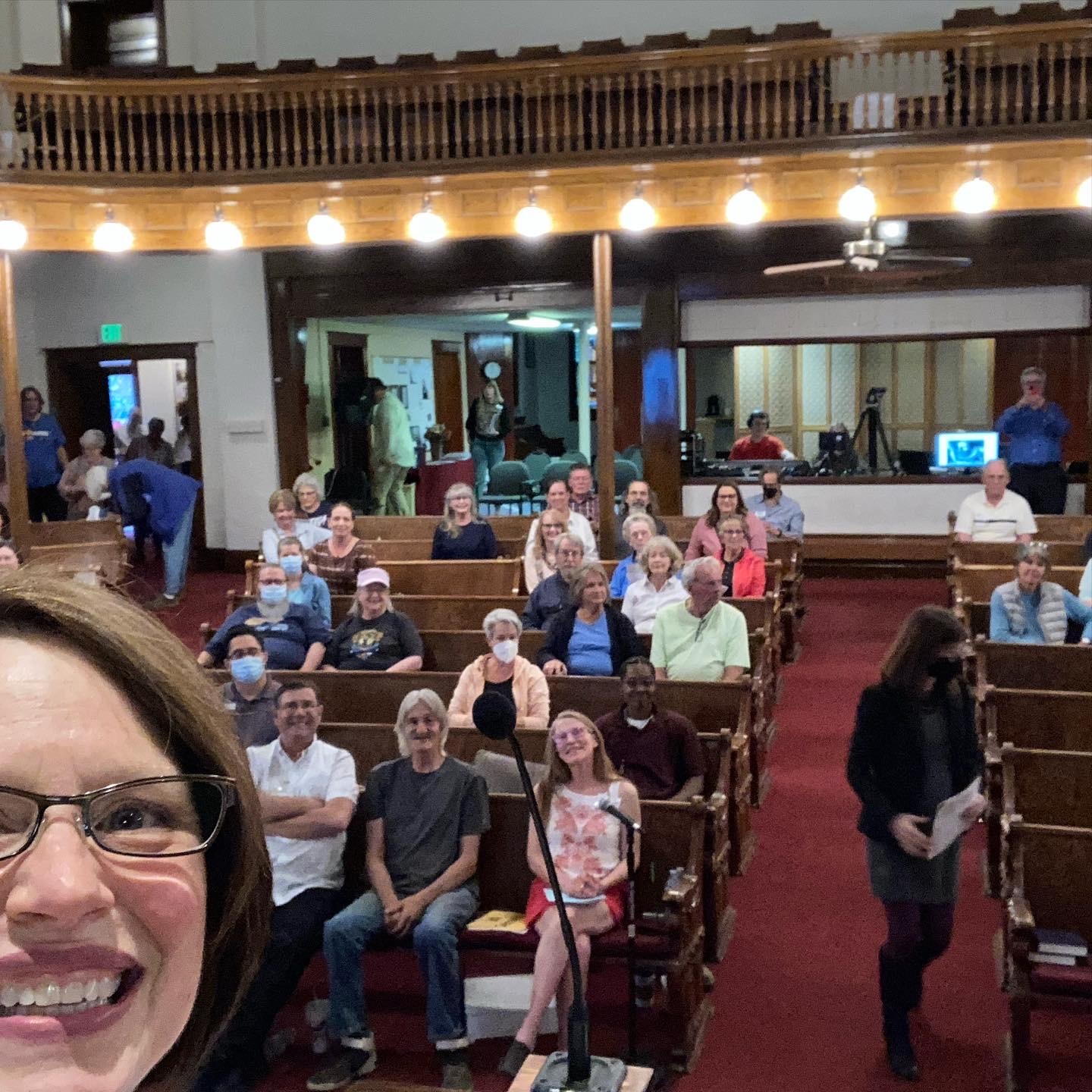 Woman taking selfie at front of church with congregants behind her