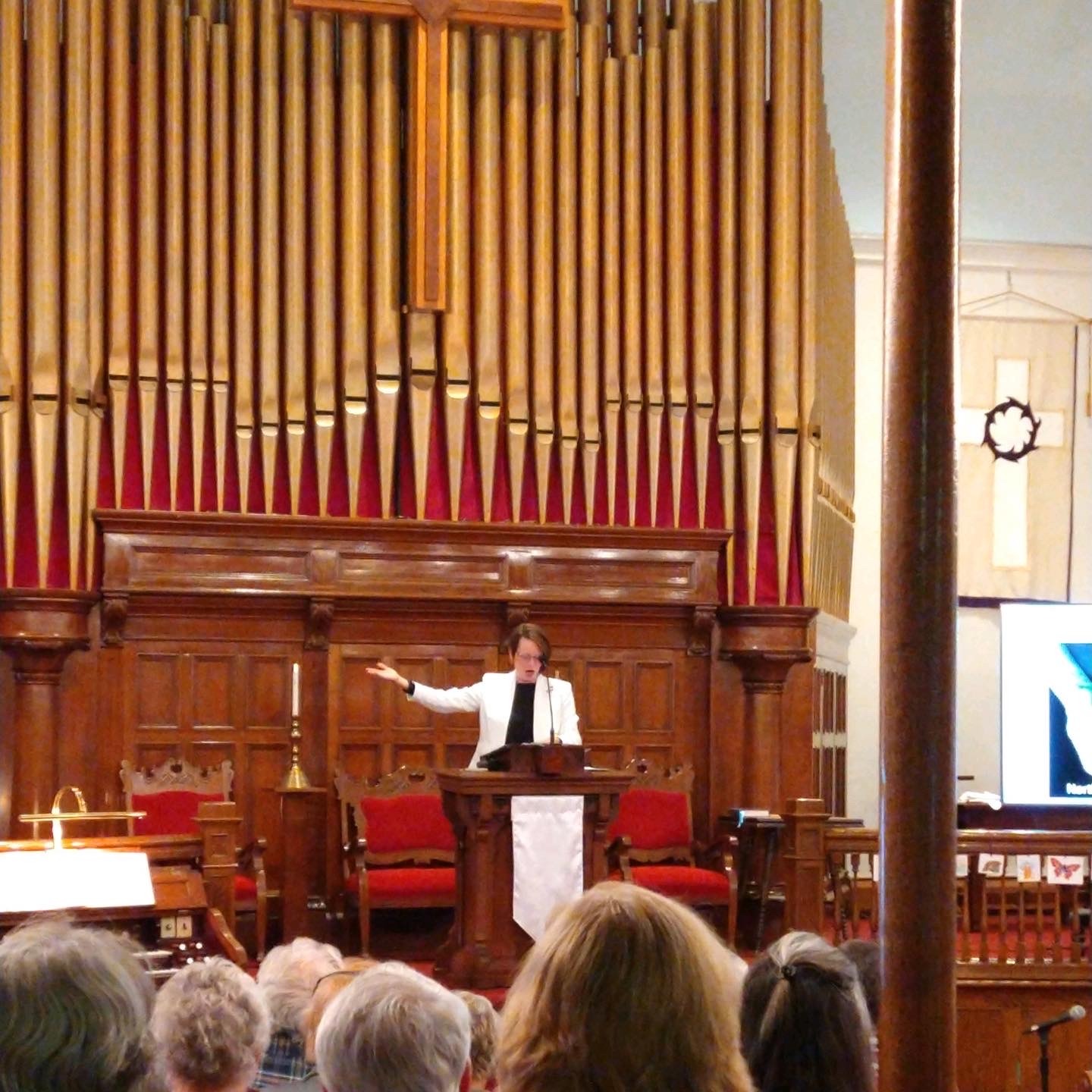 Pastor in front of congregation during Together Colorado Public Meeting